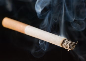 lit cigarette on black background with smoke