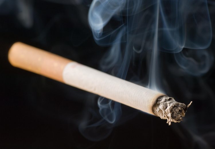 lit cigarette on black background with smoke