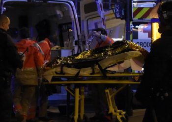 Rescue workers evacuate an injured person near the Bataclan concert hall in central Paris, on November 13, 2015. A number of people were killed and others injured in a series of gun attacks across Paris, as well as explosions outside the national stadium where France was hosting Germany. AFP PHOTO / DOMINIQUE FAGET