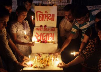 Indians place candles as they remember last years gang rape and murder of a young woman in New Delhi, in Ahmadabad, India, Saturday, Dec. 14, 2013. The victim, a 23-year-old physiotherapy student, was heading home with a male friend after an evening showing of the movie "Life of Pi" when six men lured them onto a private bus. With no one else in sight, they beat the man with a metal bar, raped the woman and used the bar to inflict massive internal injuries. Placard in center reads, "Nirbhaya, or fearless, a name given to the victim by the media, salute to your fight". (AP Photo/Ajit Solanki)