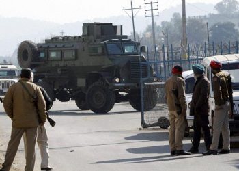 Pathankot:  Security men stand guard as an armored vehicle moves near the Indian Air Force base that was attacked by militants in Pathankot, Punjab on Saturday. PTI Photo  (PTI1_2_2016_000064B)