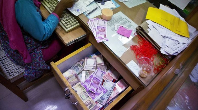 A bank employee counts discontinued currency notes while working at a currency exchange counter at a bank in Gauhati, India, Friday, Nov. 11, 2016. People queued up outside banks for the second day to exchange currency notes after Indian Prime Minister Narendra Modi, delivering one of India's biggest-ever economic upsets, declared that the bulk of Indian currency notes no longer held any value and asked anyone holding those bills to take them to banks to deposit or exchange them. (AP Photo/ Anupam Nath)