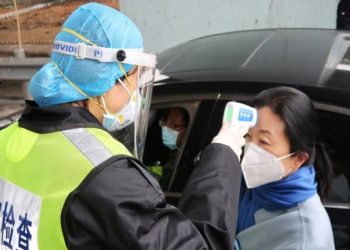 A security officer in a protective mask checks the temperature of a passenger following the outbreak of a new coronavirus, at an expressway toll station on the eve of the Chinese Lunar New Year celebrations, in Xianning, a city bordering Wuhan to the north, Hubei province, China January 24, 2020. REUTERS/Martin Pollard