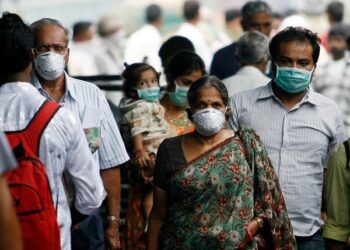 Travellers with masks walk on a railway platform in Pune August 18, 2009. Pune has reported the highest number of deaths caused by H1N1 influenza virus in India, according to a government statement released on Monday.    REUTERS/Arko Datta (INDIA SOCIETY HEALTH) - RTR26U0N