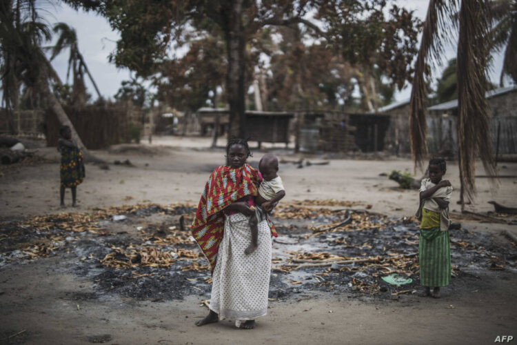 A woman holds her younger child while standing in a burned out area in the recently attacked village of Aldeia da Paz outside Macomia, on August 24, 2019. - On August 1, the inhabitants of Aldeia da Paz joined the long list of victims of a faceless Islamist group that has been sowing death and terror for nearly two years in the north of the country, which welcomes from September 4 the Pope. (Photo by MARCO LONGARI / AFP)
